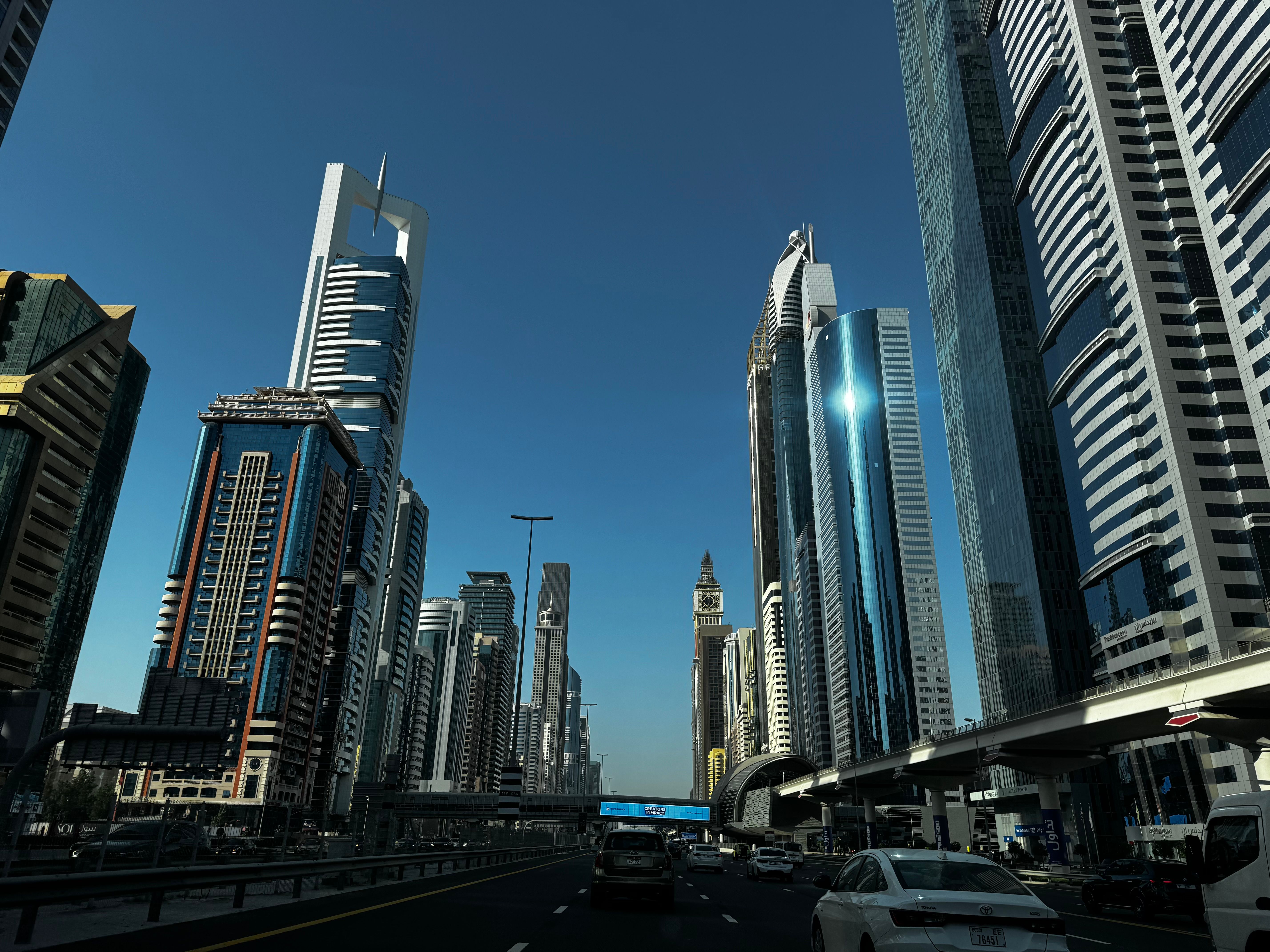 Sheikh Zayed Road in Dubai: towers, a metro line, blue sky.