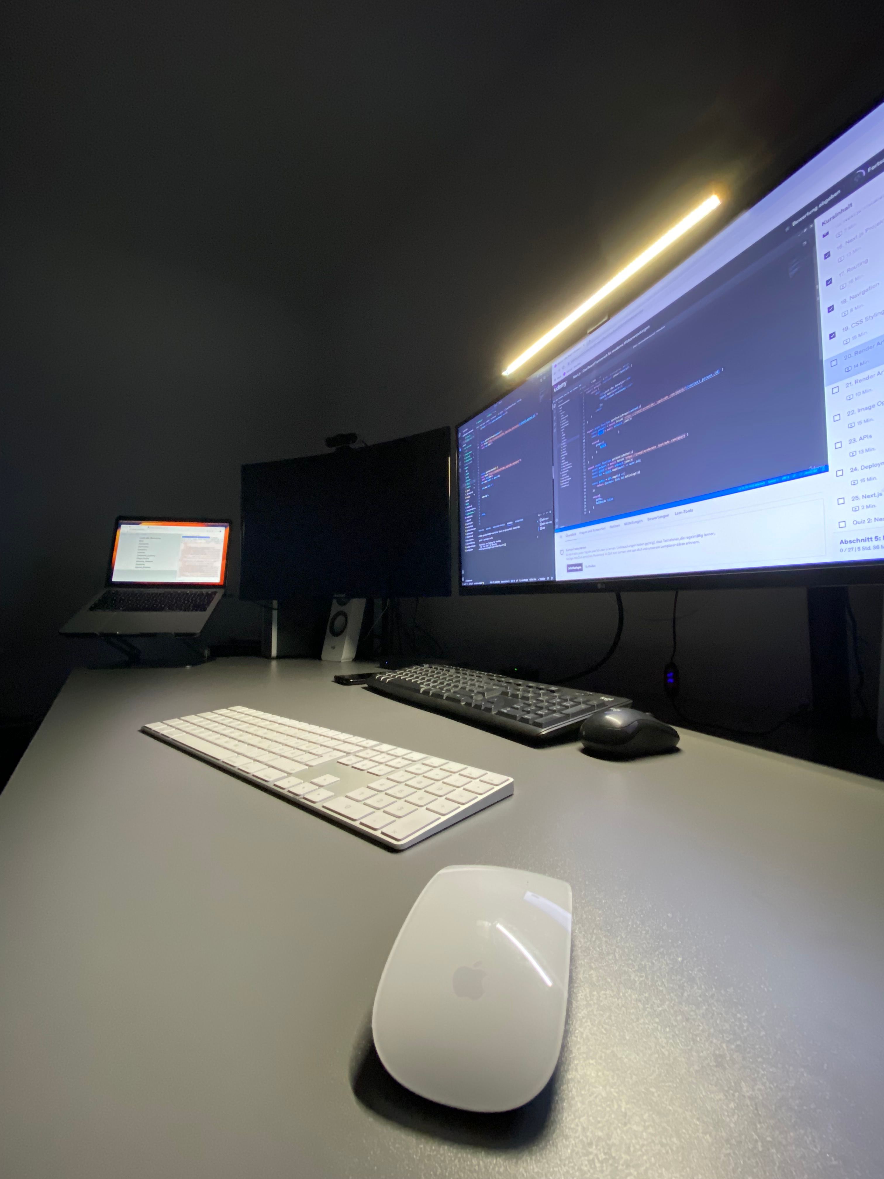 My desk at the start of my developer years: two monitors with code, a laptop, a lamp strip.